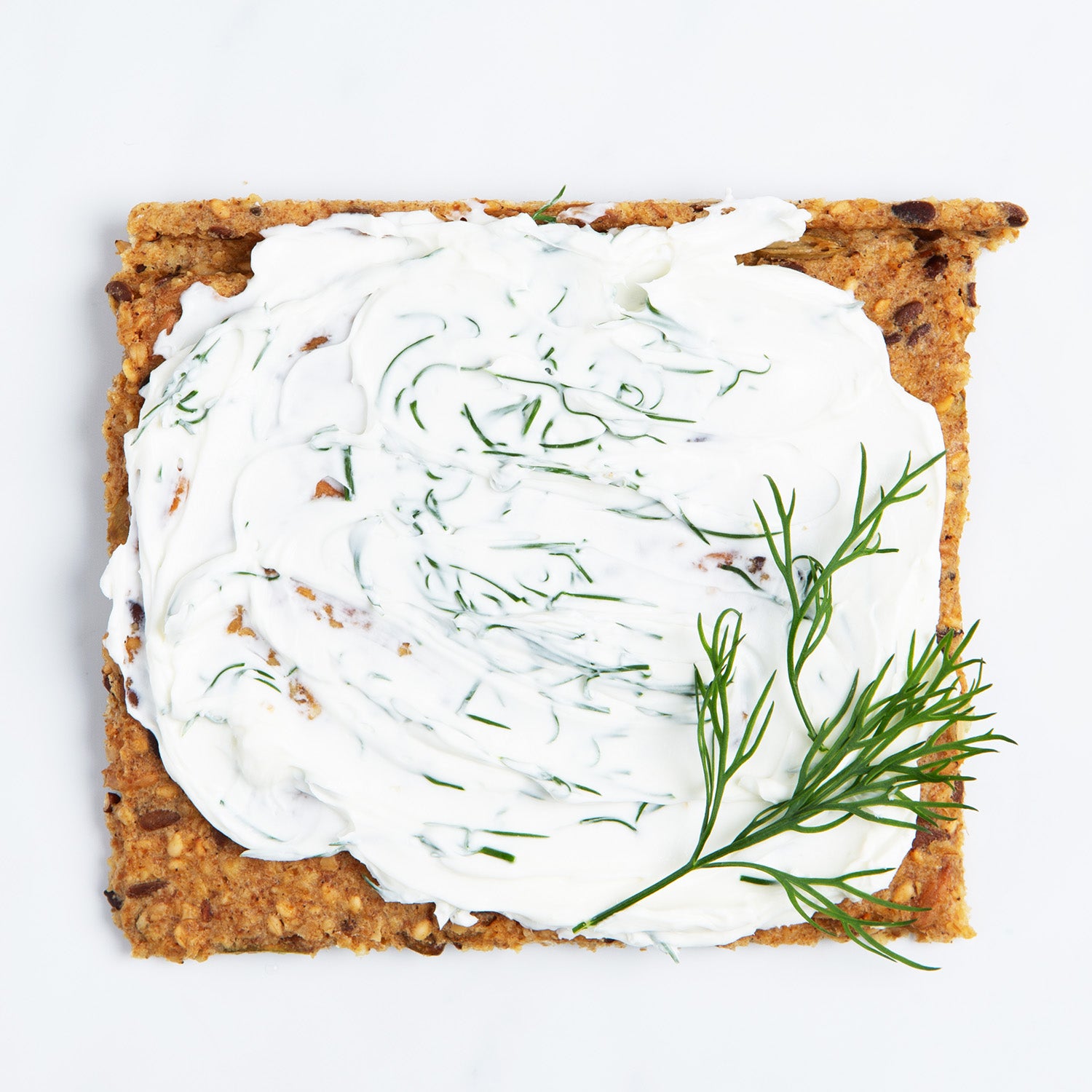 Chili and Coriander Knekkebrød served with cream cheese and dill on a white background