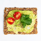 Chili and Coriander Knekkebrød served with avocado spread on a cracker with cherry tomatoes and parsley