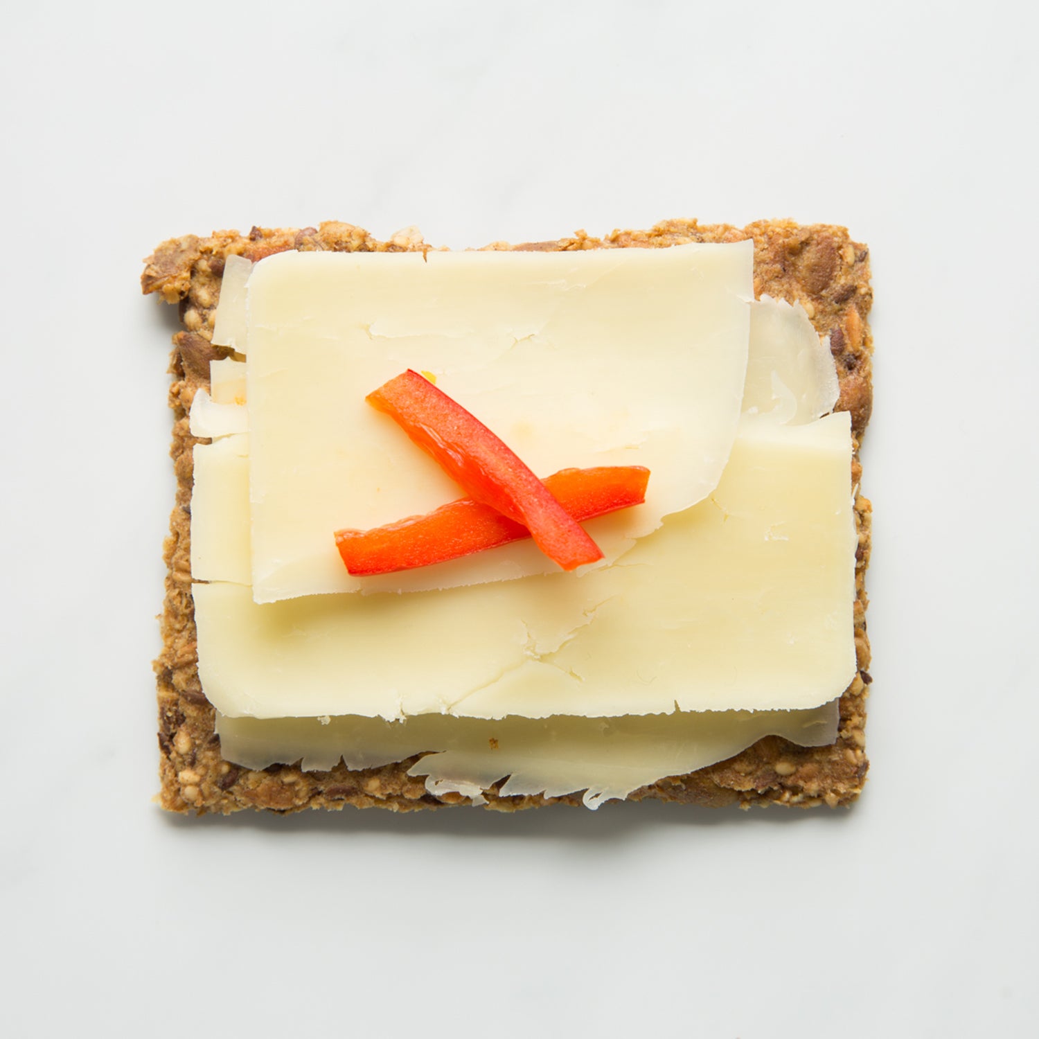 Classic crispbread with cheese and red pepper on a white background