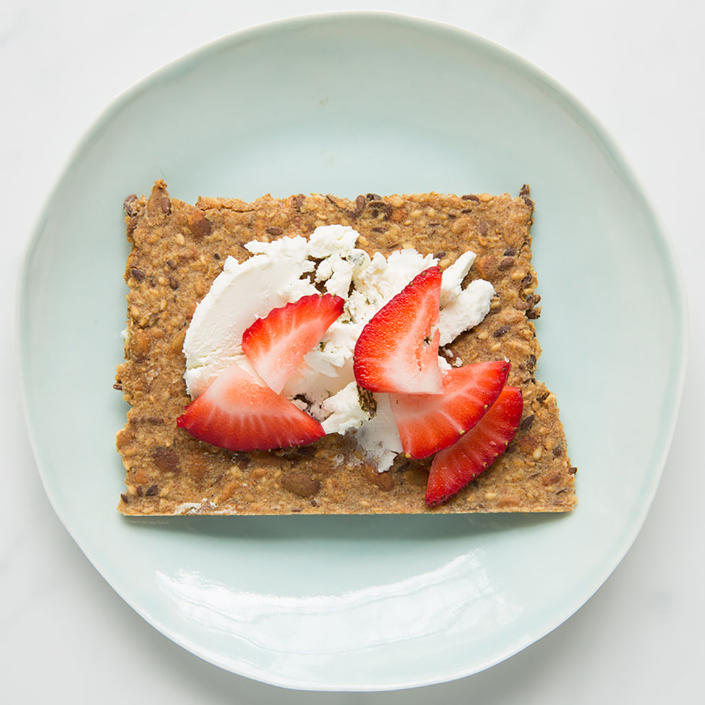 Overhead of Classic Knekkebrød crispbread with goat cheese and strawberries on a light blue plate