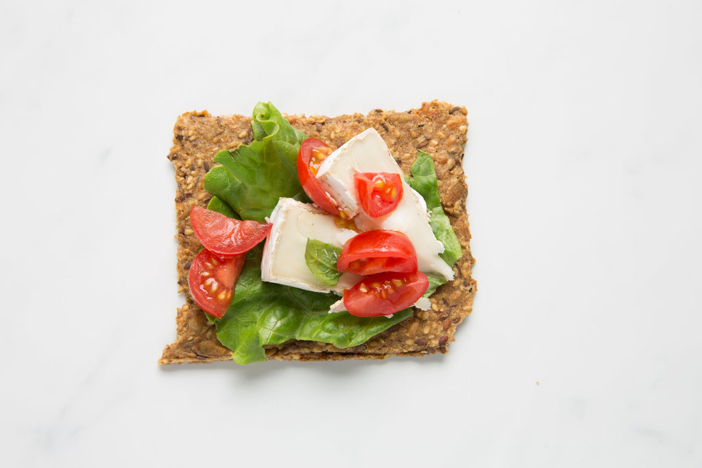 Close-up of Rosemary Lemon Knekkebrød  with tomatoes, brie cheese, and lettuce on a white background