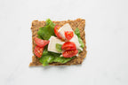 Close-up of Rosemary Lemon Knekkebrød  with tomatoes, brie cheese, and lettuce on a white background