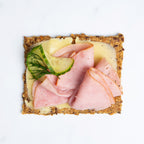Close up of  Sea Salt Flakes Knekkebrød crispbread with sliced ham, cheese, and pickles.
